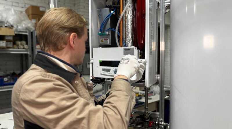 Technician installing or repairing a heating system in an indoor workshop setting. - Photo by МОБО Модульные Котельные on Pexels